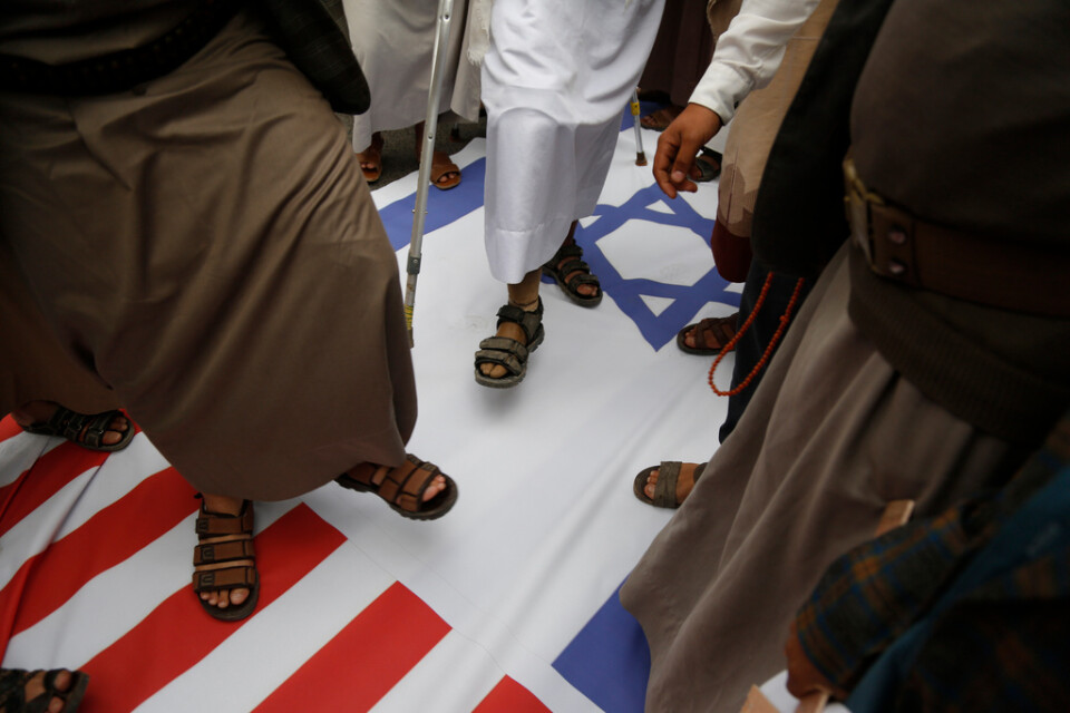 Anhängare till huthirebellerna trampar på amerikanska och israeliska flaggor under en demonstration i Sanaa, Jemen, i mars. Arkivbild.