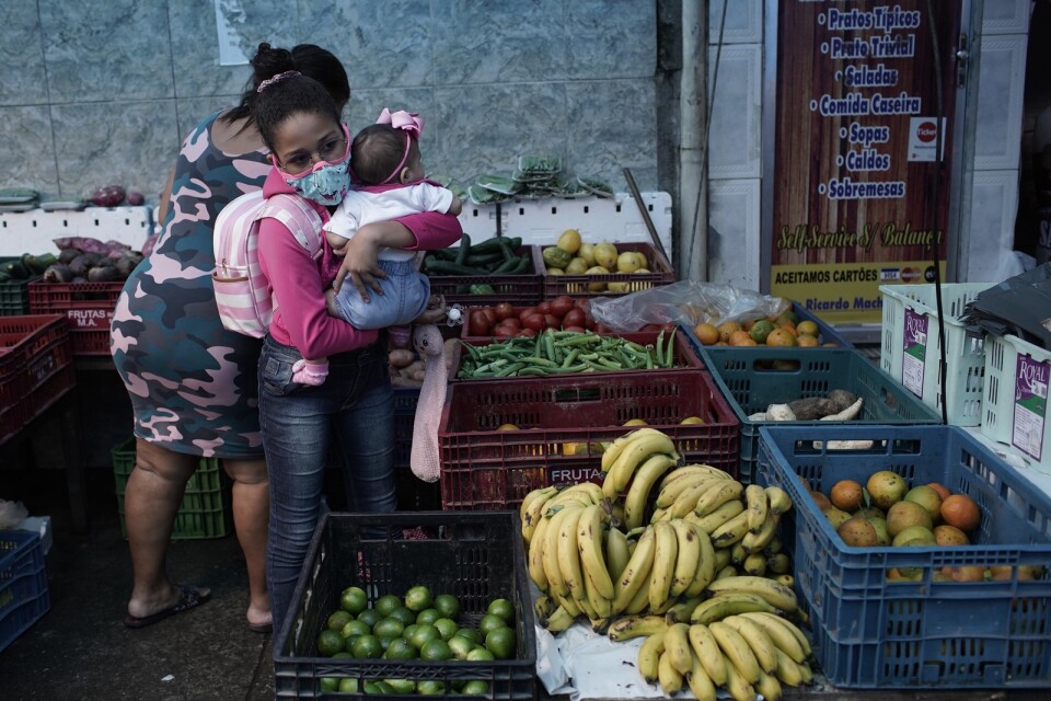 En kvinna med en bebis köper frukt i Rio de Janeiro.