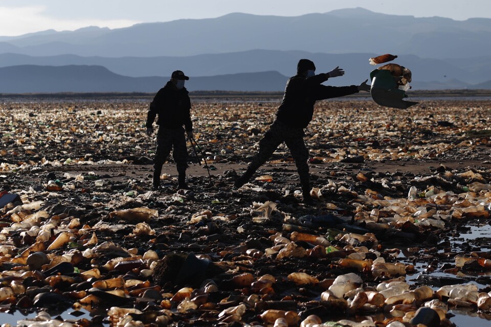 Poliser i Bolivia rensar skräp från en flod som översvämmats av plastavfall. Arkivbild.
