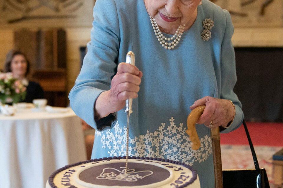 Drottning Elizabeth|II skär upp tårta till inbjudna invånare i Sandringham i England.