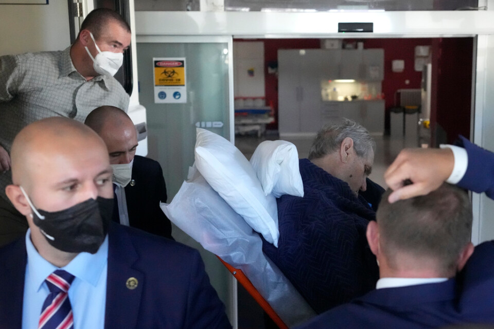 Milos Zeman (med hängande huvud till höger) på väg in på sjukhuset UVN i söndags.