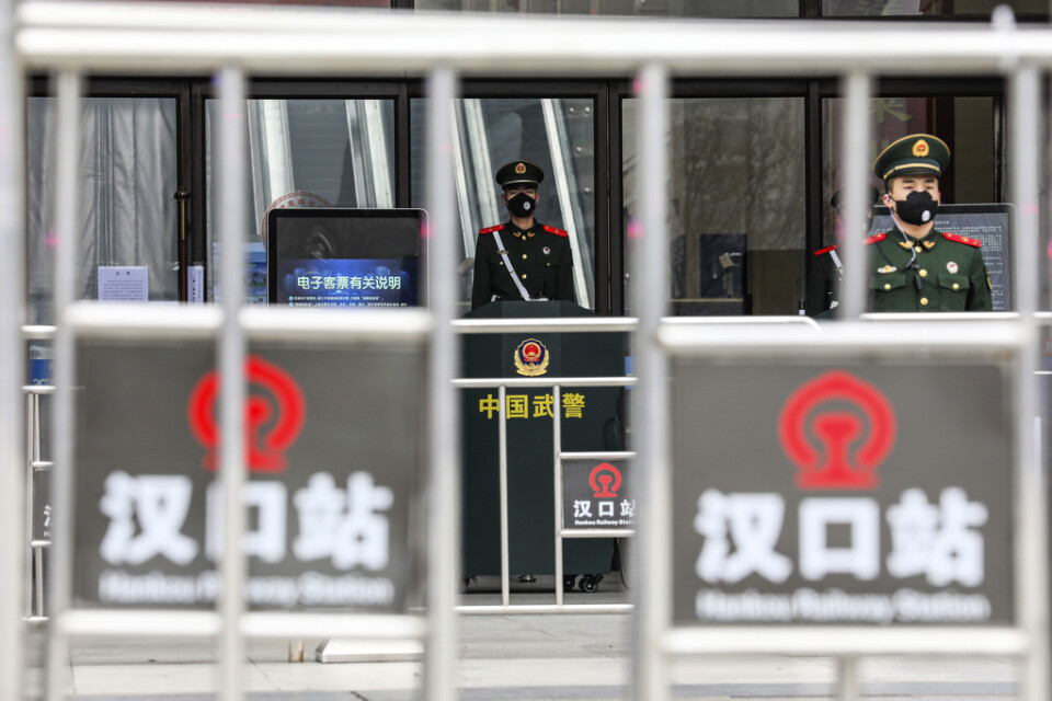 Poliser vaktar en stängd tågstation i Wuhan i Kina.