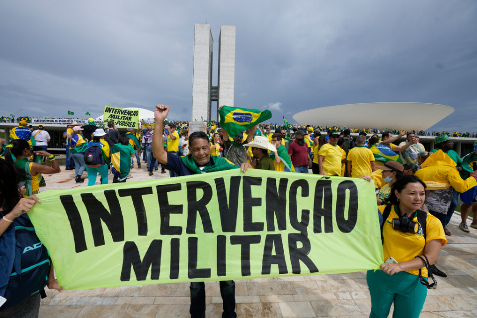 Demonstranter som stödjer expresidenten Jair Bolsonaro under söndagens stormningen av kongressen i Brasília. "Militär intervention" står det på banderollen.