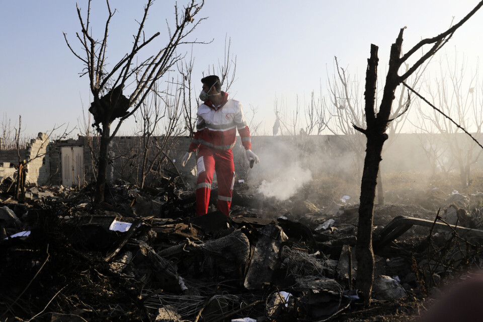 Räddningsarbetare söker igenom platsen för flygkraschen i Iran.