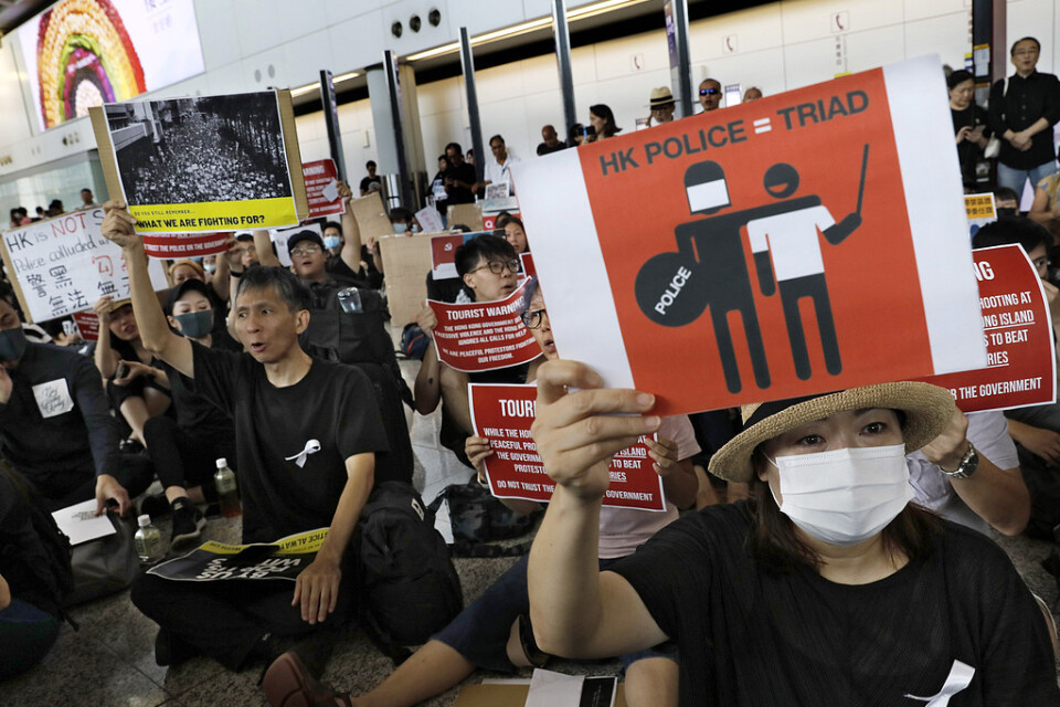 Demonstranter håller upp plakat under en protest på Hongkongs flygplats.