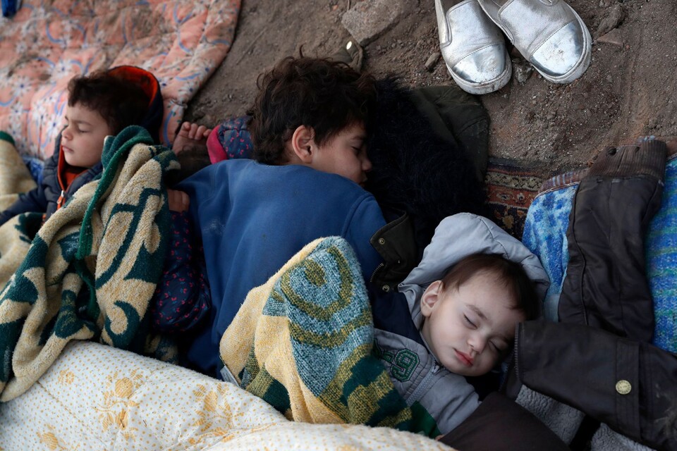 Utmattade barn sover på marken invid floden som utgör gräns mellan Turkiet och Grekland.
