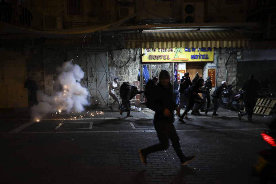 Palestinier flyr från polisens distraktionsgranater under sammandrabbningar i östra Jerusalem på torsdagskvällen.
