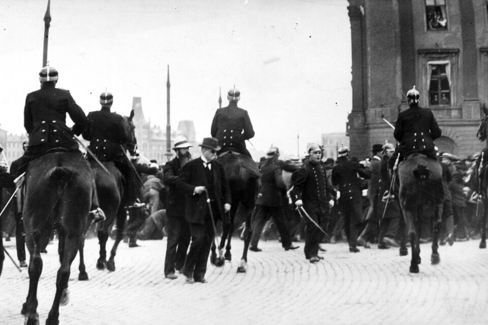 Ridande polis försöker skingra massan under hungerdemonstrationer i Stockholm 1917, Mitt  bilden syns politikern Hjalmar Branting.