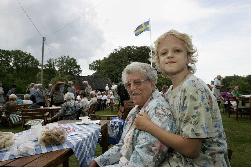 Svea Andersson och barnbarnet Linus Andersson sitter och myser i sensommarvädret ute i Lilla Tockarp.