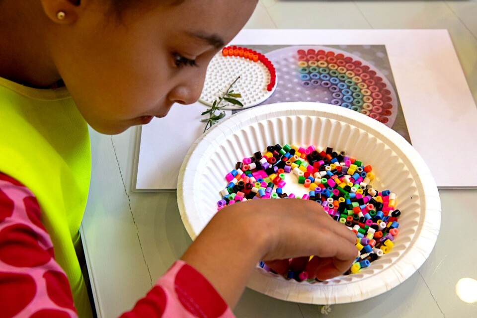 Nour Hamidi, fem år, botaniserar bland pärlorna som bär regnbågens alla färger.