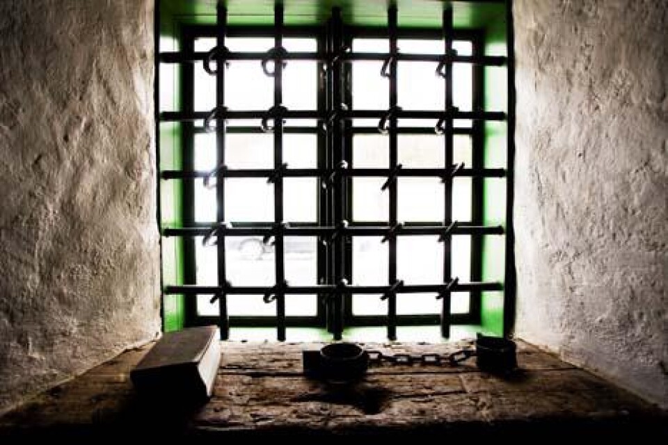 Fotbojor och bibel i fönstersmygen på det som var männens cell i Klörups häkte. Bakom gallren utsikt mot smedjan tvärs över gatan.