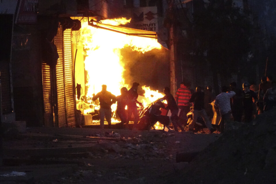 En butik sätts i brand av demonstranter under de våldsamma sammandrabbningarna i New Delhi under tisdagen.