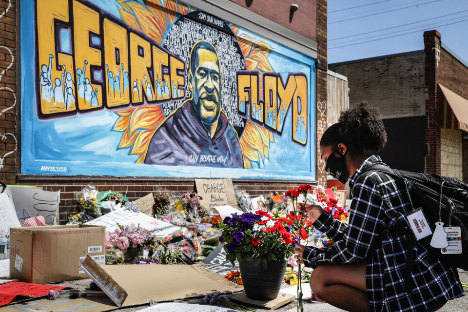 En ung kvinna lägger ner blommor framför en muralmålning av George Floyd i Minneapolis där han dog i samband med ett polisingripande. Många världsledare fördömer händelserna kring Floyds död.