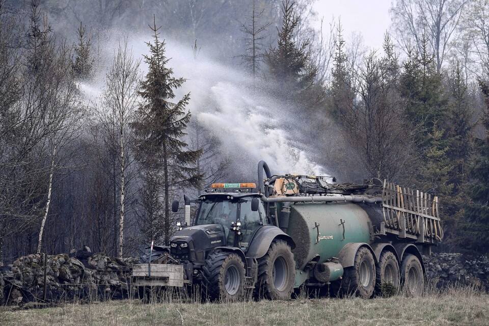 Traktorer med gödseltankar vattenbegjuter skogen kring begränsningslinjen vid den nerbrunna hästgården vid Tulatorp utanför Hästve.Branden rasade i flera dagar. 
Foto: Johan Nilsson / TT