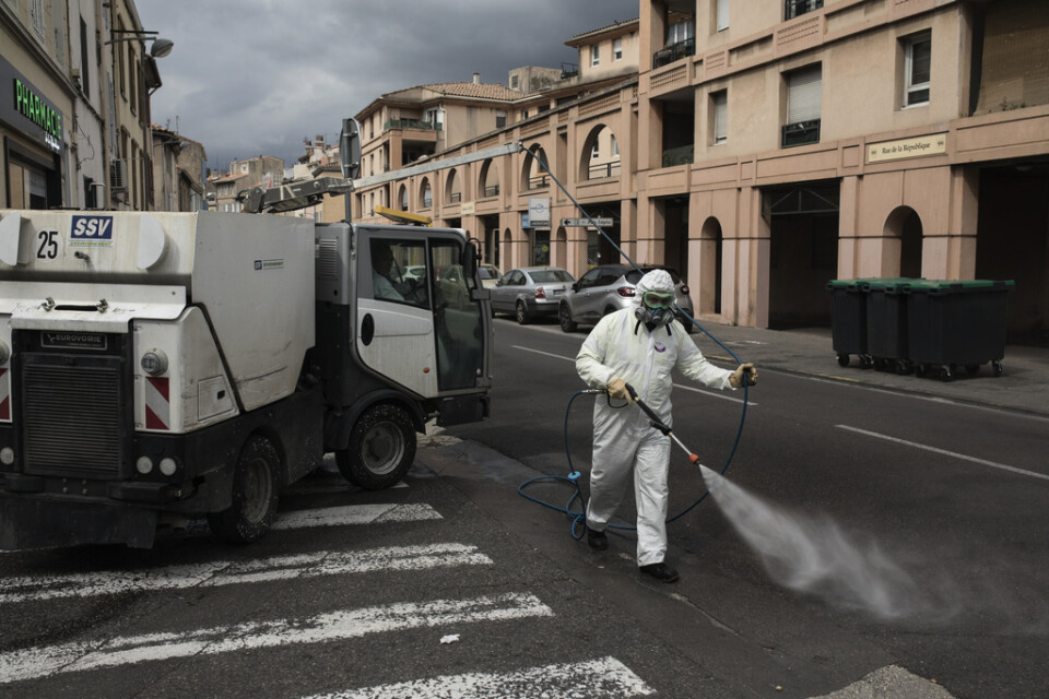 En man i skyddsklädsel sprejar desinfektionsmedel i staden Aubagne i södra Frankrike.