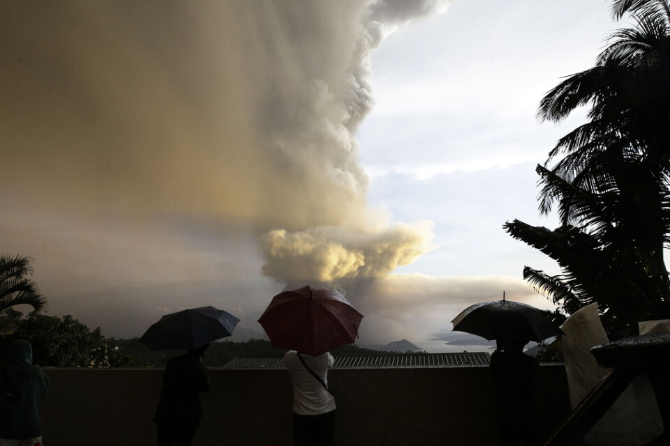 Människor beskådar vulkanen Taal, som sprutar aska utanför Manila.