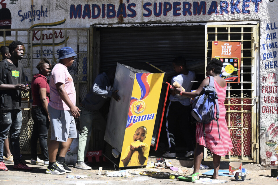 Plundrare vid en förstörd butik i utkanten av den sydafrikanska staden Johannesburg. Arkivbild.