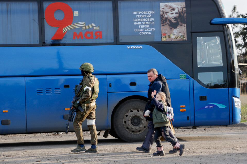 En man och en flicka förs till en buss av en rysk soldat för att lämna Mariupol. Bild från 6 maj.