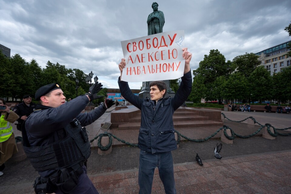 En polis griper en demonstrant i Moskva med en skylt vars text lyder "Frihet för Alexej Navalnyj".
