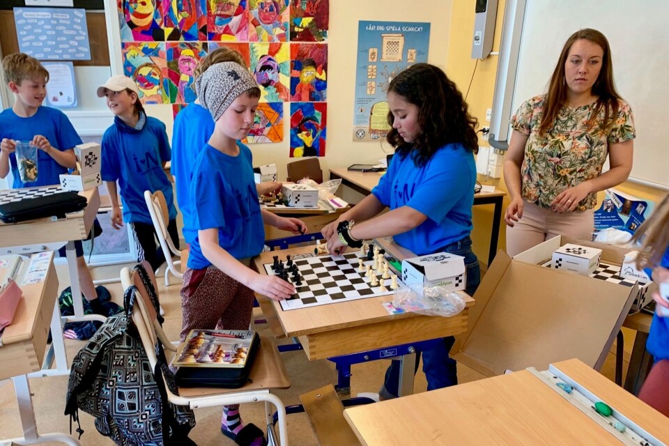 Mira Andersson och Isabelle Christy Stoltz förbereder ett parti. Michaela Lindgren hjälper eleverna att plocka fram schackbrädor.