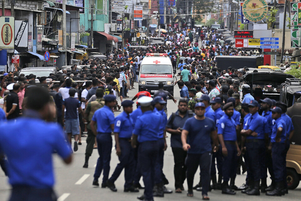 Poliser i Sri Lanka försöker ge fri väg åt en ambulans.