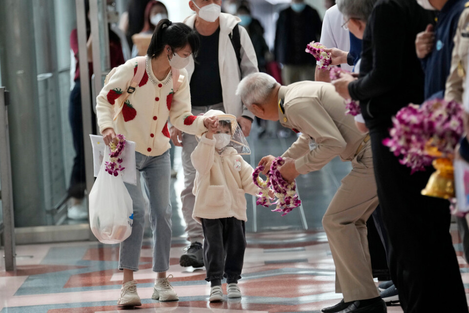 Kinesiska turister får blommor när de anländer på Bangkoks storflygplats Suvarnabhumi på måndagen.