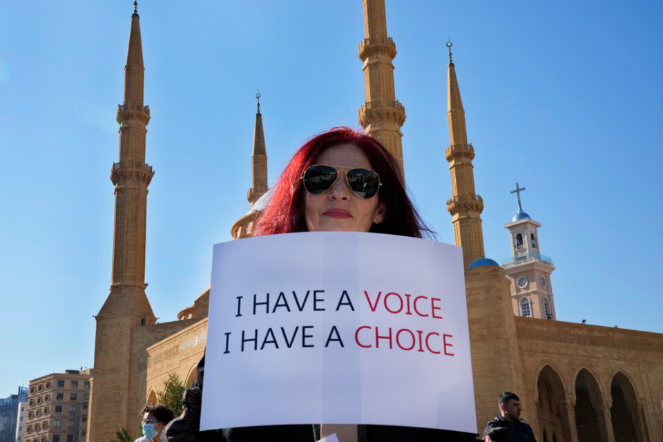 En kvinna håller upp ett plakat under en protest mot Libanons virusåtgärder, som slår särskilt hårt mot ovaccinerade.