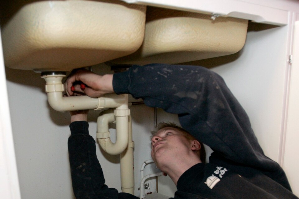 En VVS-tekniker, rörmokare jobbar med rör under en diskho