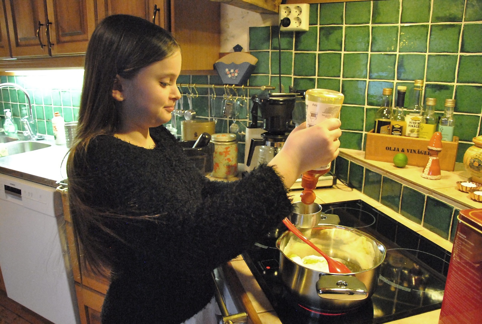 Emmy Tennevi, 11 år, har utnämnt sig själv till boss i köket och hon verkar ha koll på läget. Här häller hon ner sirap i kastrullen för att göra kola. 
Foto: Marie Strömberg Andersson