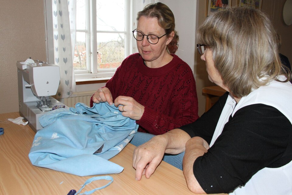 Heléne Wickléus och Kristina Jacobsson gör ändringar på en klänning som en kvinna kommit och bett om hjälp med.