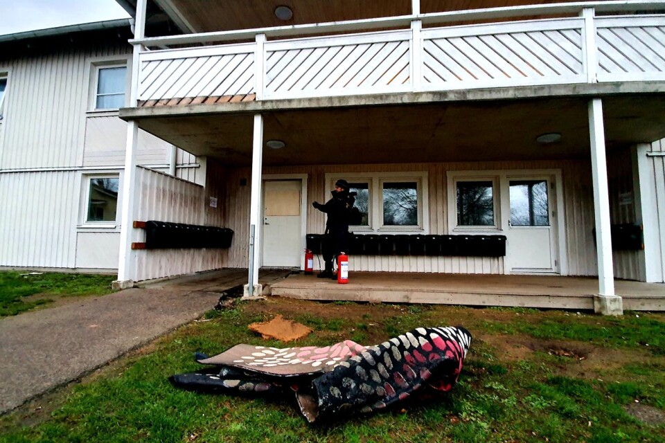 En matta och några dukar på gräsmattan framför byggnaden vittnar om de boendes försök att släcka branden i fastigheten.