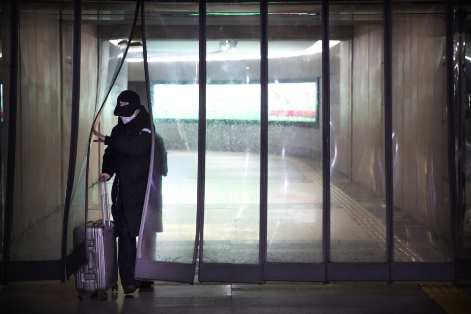 En person med ansiktsmask vid en tunnelbanestation i Kinas huvudstad Peking på söndagen.
