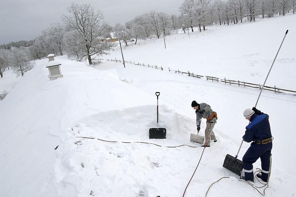 Antoni Bogdar och Attila Nemeth har flera dagars arbete med att få bort snön från ladugårdstaket i Flöxhult. Foto: Stewe Jonsson