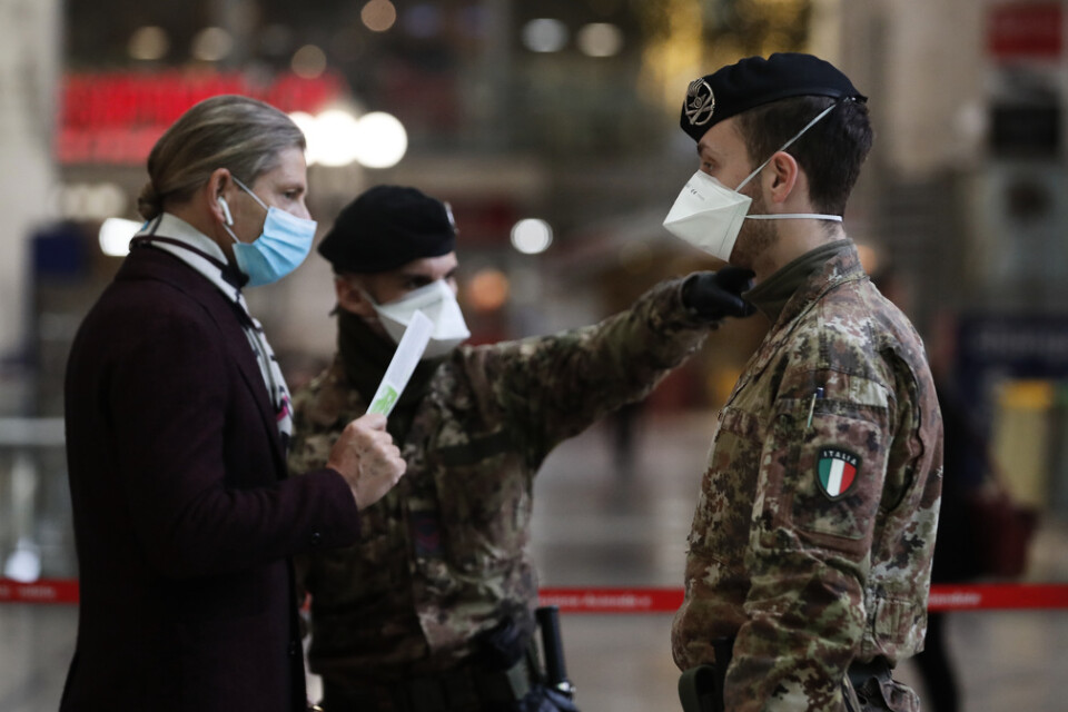 Resande på centralstationen i Milano i Italien kontrolleras av militär.