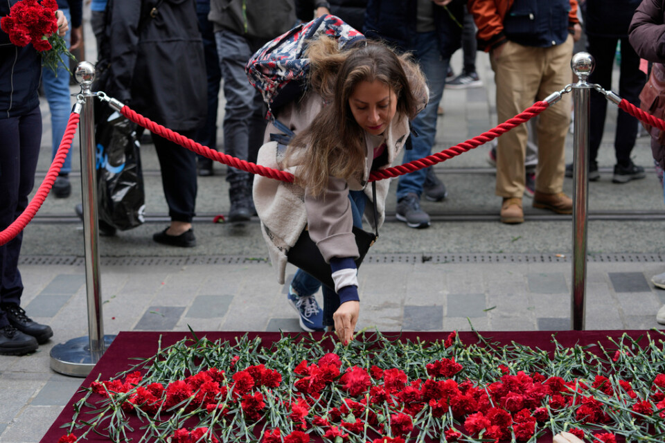 En kvinna lämnar en blomma vid minnesplatsen som upprättats på gågatan Istiklal i centrala Istanbul dagen efter dådet.