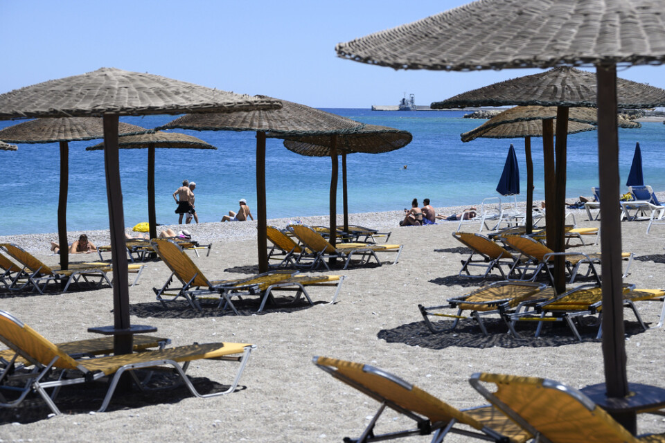 Turister njuter av solen på en strand på den grekiska ön Rhodos. Arkivbild.