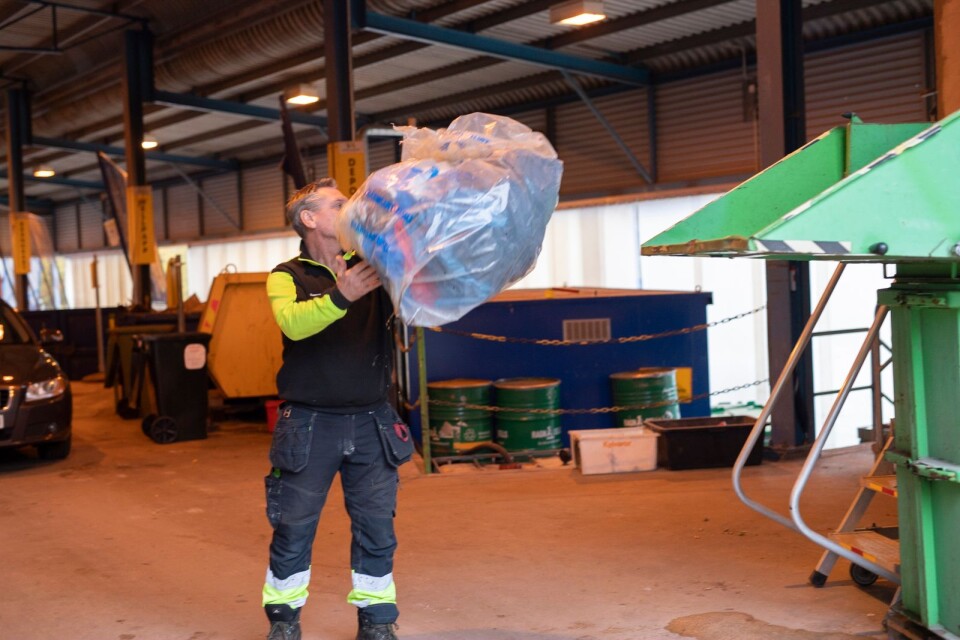 Conny Månsson slänger utsorterad mjukplast i en komprimator på återvinningscentralen i Tollarp.