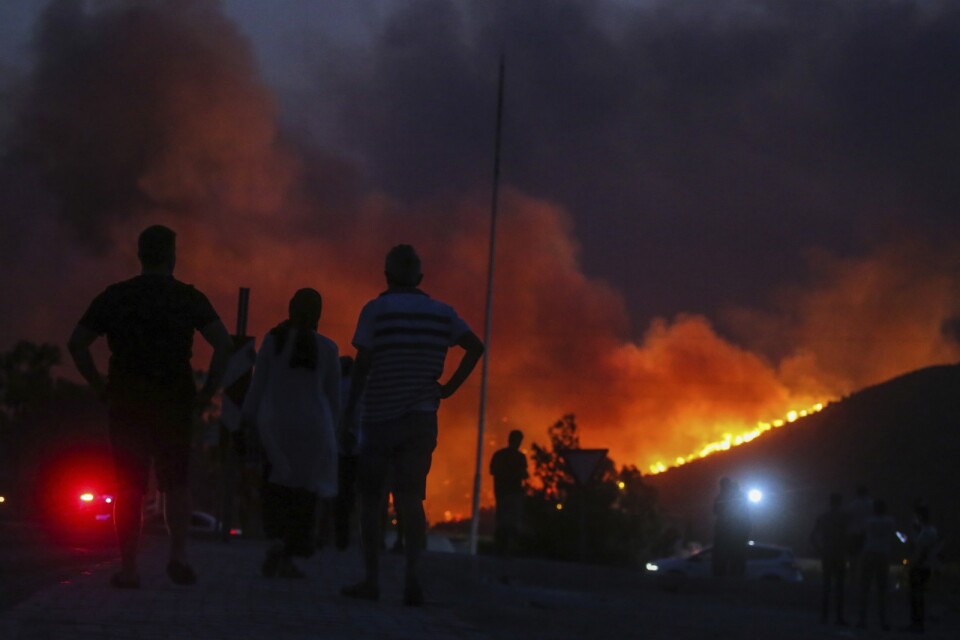 Människor framför det brinnande Kemerkoy-kraftverket i Milas i sydvästra Turkiet.