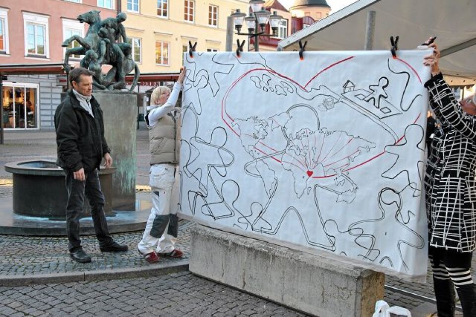 Konstnärerna Pernilla Persson till vänster och Stina Brodén sätter upp den stora skissen som ska fyllas i av allmänheten. Målningen kommer att auktioneras ut på lördag eftermiddag. Foto: Markus Danielsson