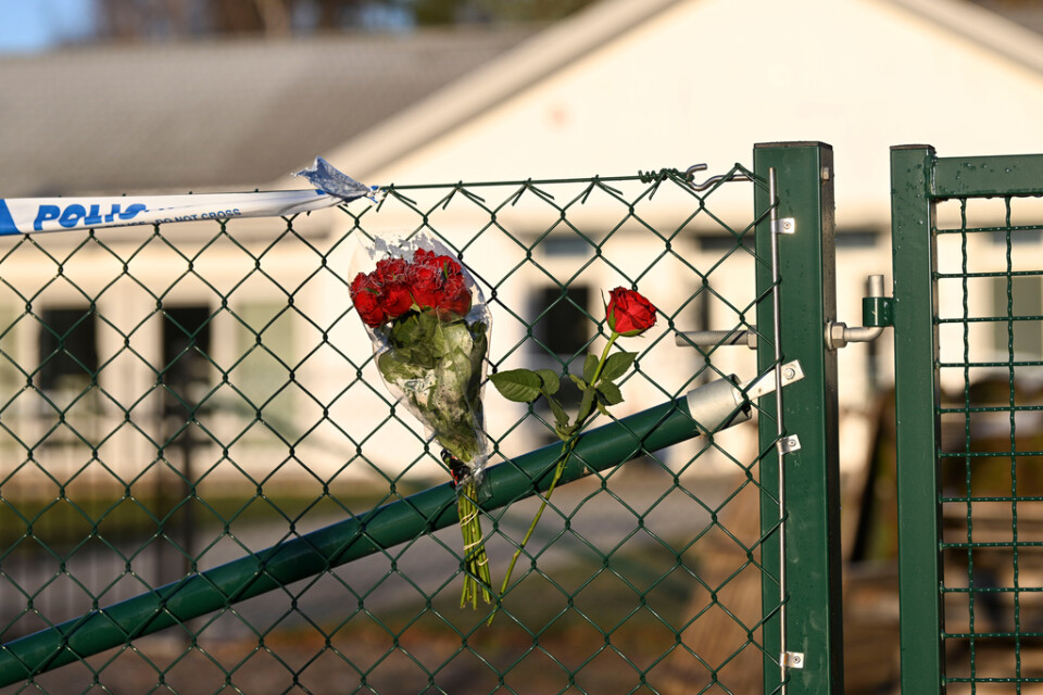 Blommor på stängslet utanför vårdboendet i Enköping där en ung kvinna i personalen dödades av en boende i november 2022.