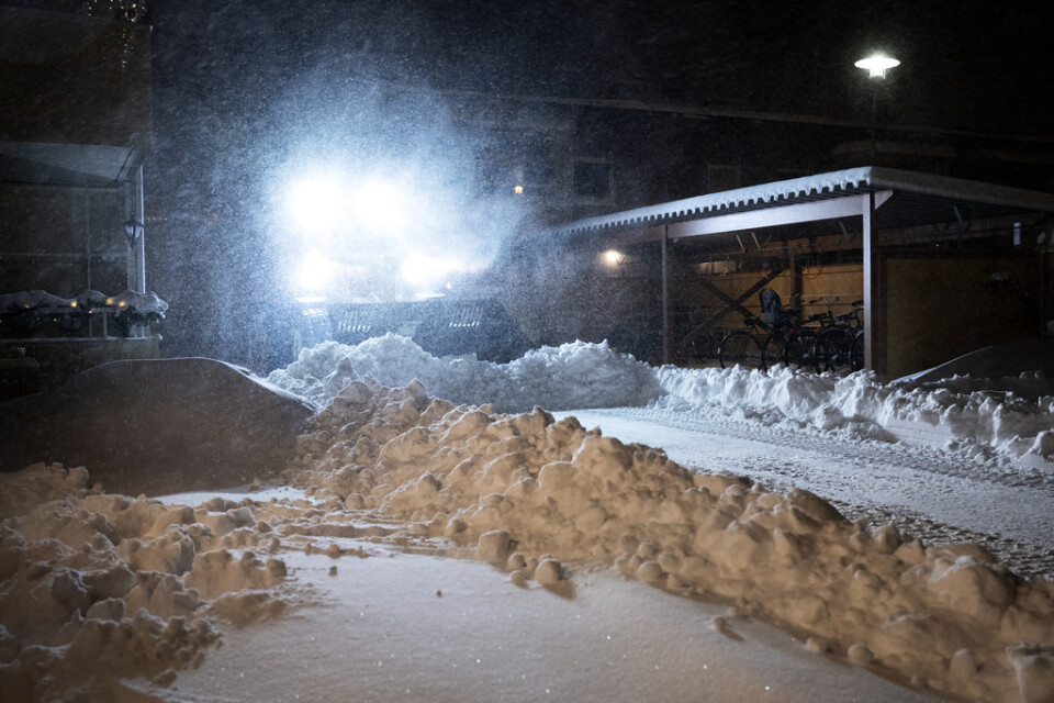 En traktor plogar bland några hus i snöovädret i Umeå, på tisdagsmorgonen den 12 januari.
