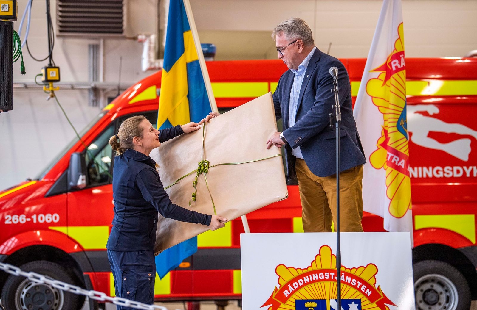 Drift- och servicenämndens Peter Johansson lämnar över en gåva till räddningschef Anna Henningsson.