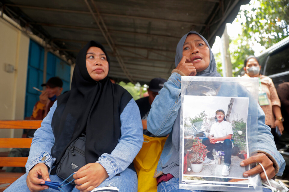 Rini Hanifah håller upp en bild på sin son, som dog i plankatastrofen i Indonesien. Nu har rättegången mot fem personer som anklagas för vårdslöshet startat.