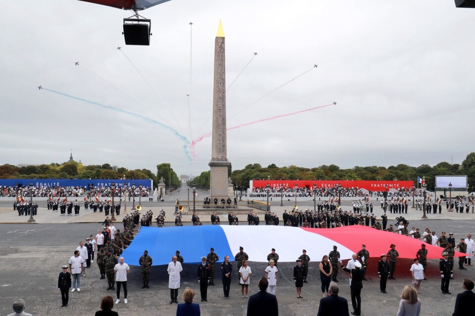 Vårdanställda tog plats vid den franska flaggan under årets decimerade nationaldagafriande vid Place de la Concorde i Paris.