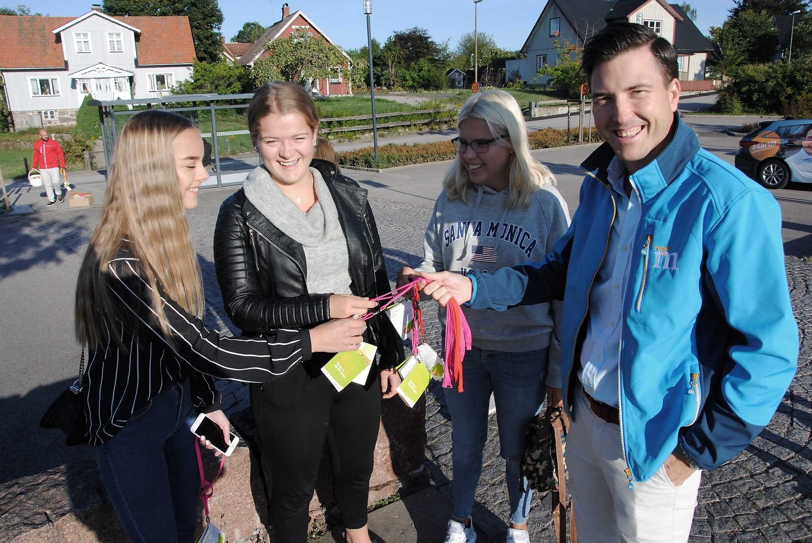 Emma Roos, Wilma Fridolin och Tova Jönsson får information om skolkortet av Patric Åberg (M) när de väntar på bussen i Glimåkra på första skoldagen.