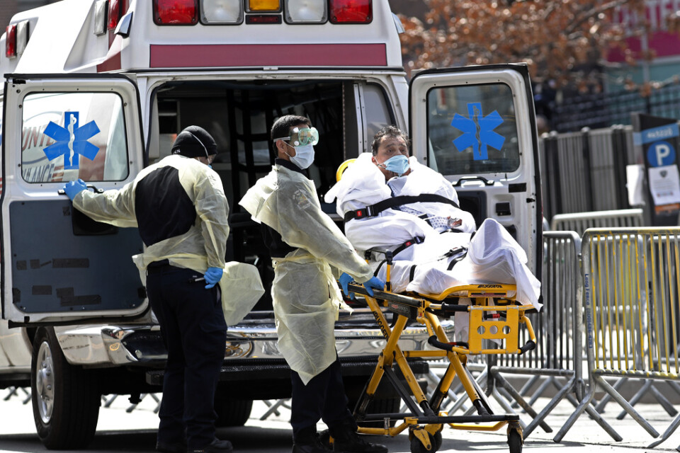 Ambulanspersonal i munskydd rullar ut en förmodad covid-19-patient vid ett sjukhus i Queens i New York.