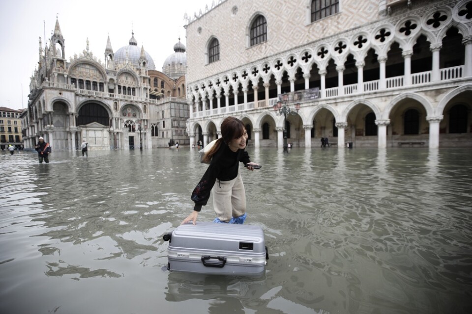 En turist skjuter på sitt bagage i vattnet på Markusplatsen i Venedig på onsdagen.