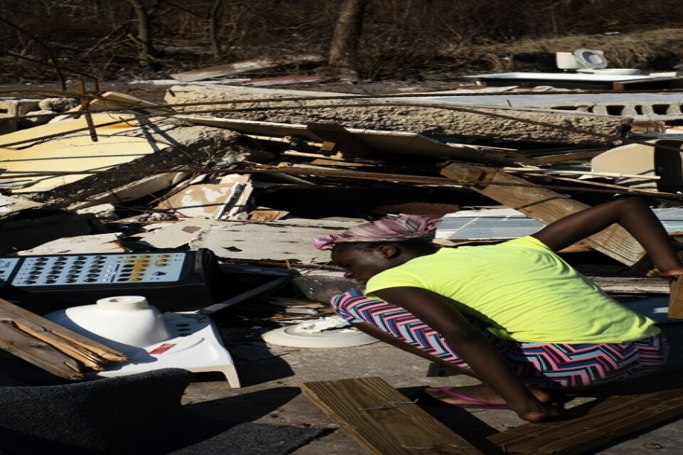 En kvinna letar efter anhöriga i spillrorna efter deras hus. Bilden är från i fredags.