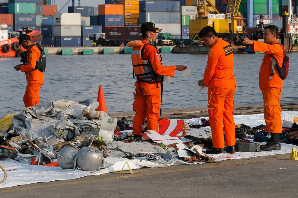 Indonesisk sökpersonal undersöker föremål i närheten av platsen där det indonesiska passagerarflygplanet störtat.