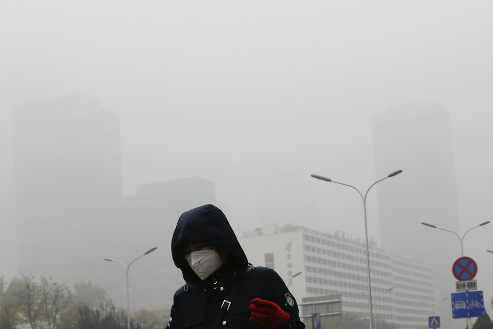 Tiotusentals människor beräknas ha dött i år till följd av luftföroreningar i Peking och Shanghai. På bilden bär en kvinna ett andningsskydd i ett smogtätt Peking. Arkivbild från 2018.